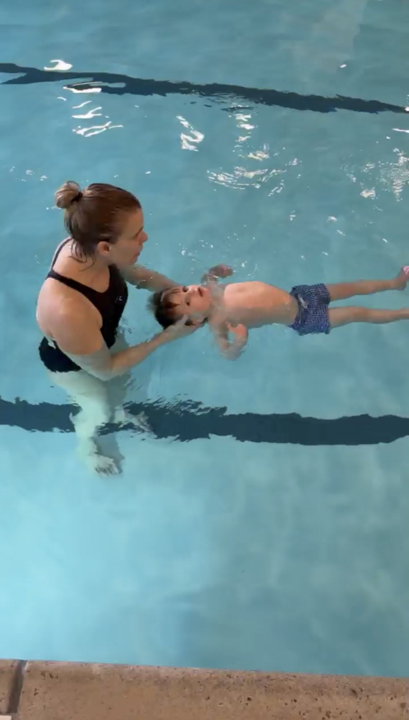 Coach supporting a young swimmer in a back float during a lesson