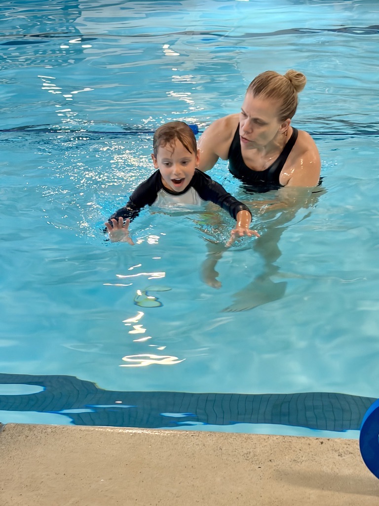 Coach guiding a young swimmer through a relaxed, balanced swim